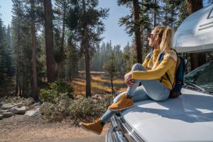 woman sitting on a vehicle's hood relaxing and enjoying nature